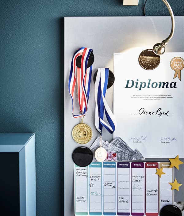 A magnetic board displays medals, a certificate and a weekly schedule.