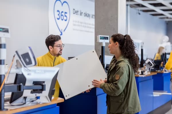 A male IKEA co-worker helps a woman with a complaint in a store.