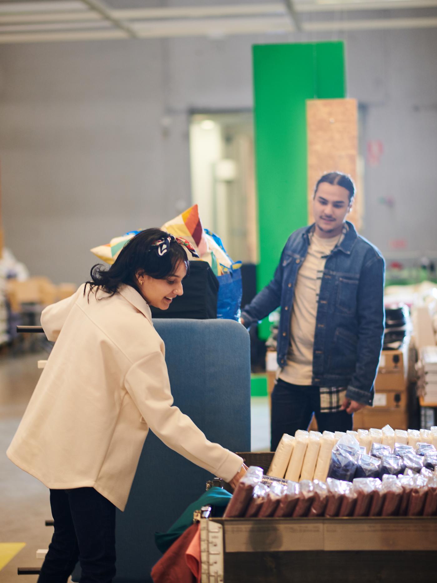 A man and a woman in the As Is department at IKEA, choosing bed linen from a product display.