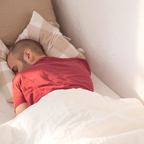 A man asleep on his front.