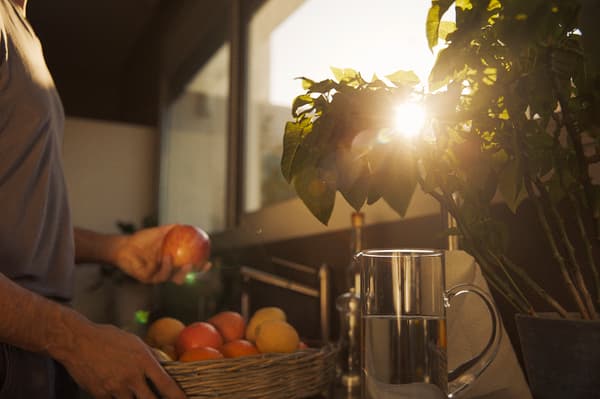 A man fetches fruit on a balcony as the sun sets.