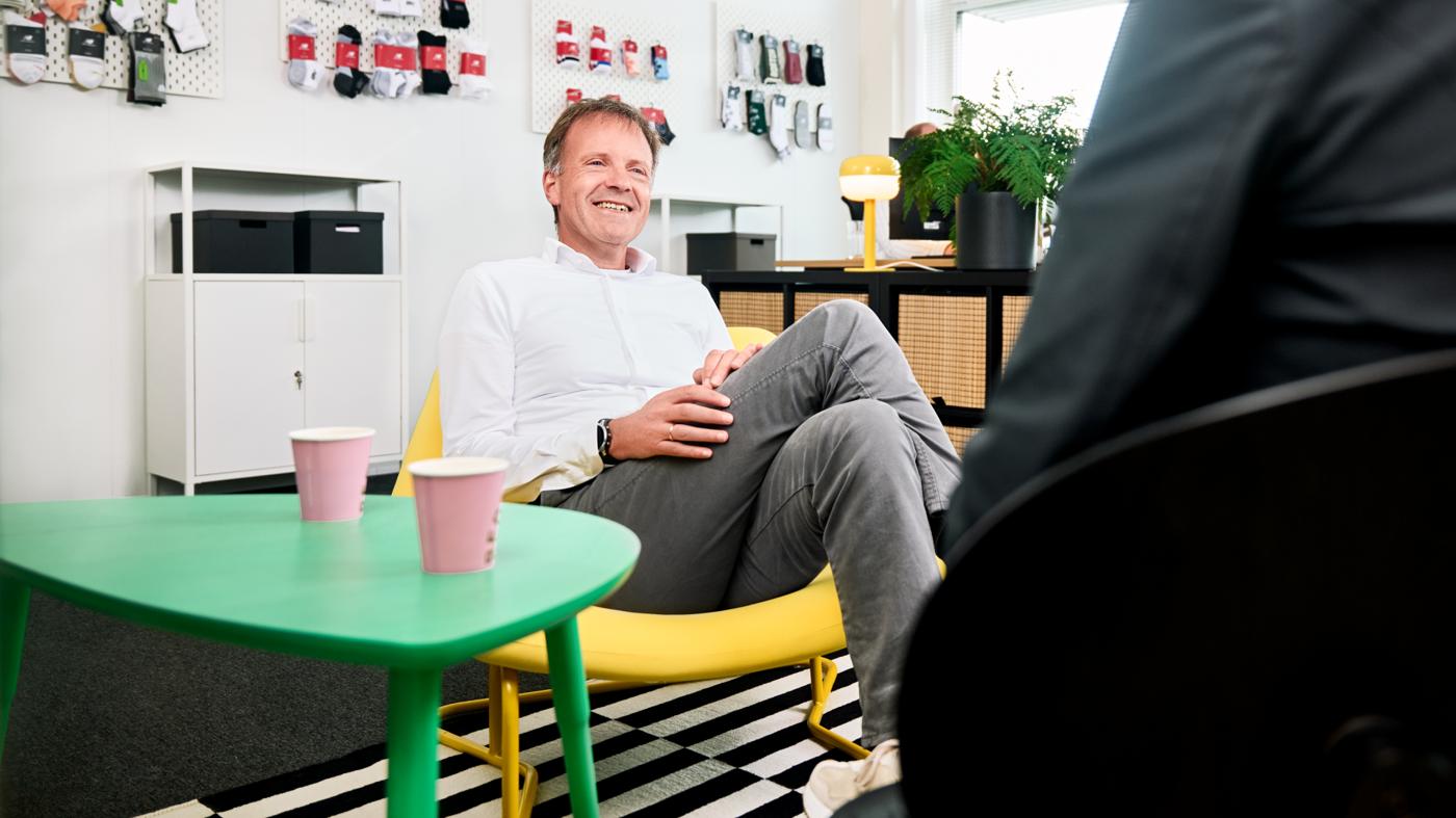 A man in an office sits on a yellow IKEA chair.