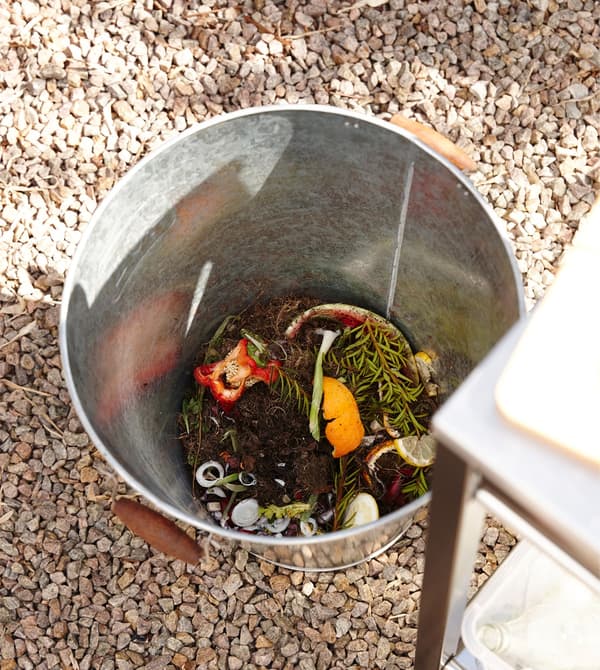 A metal bucket for compost in an outdoor kitchen.