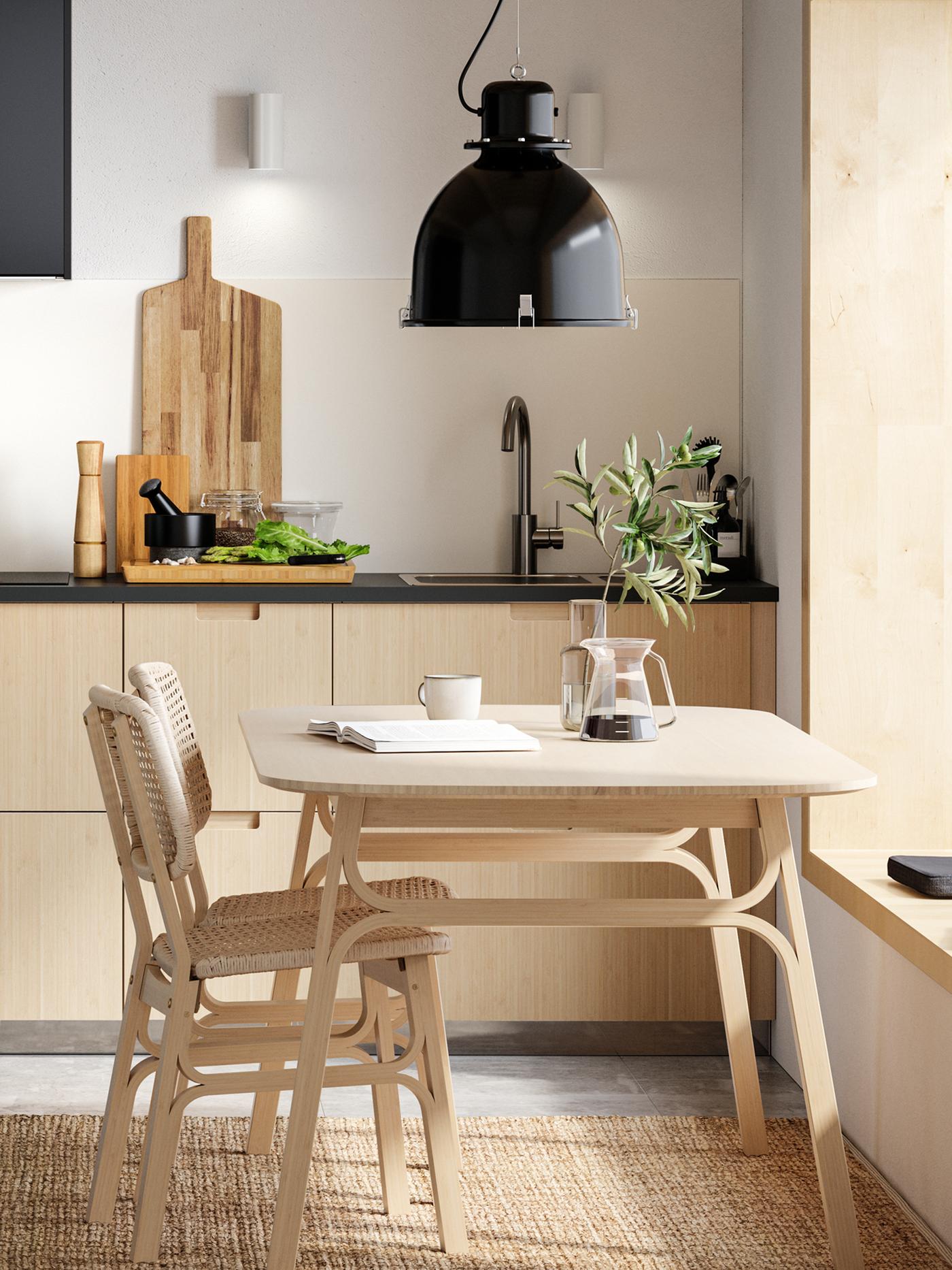 A minimalist kitchen with light bamboo drawer fronts, a light bamboo dining table and two chairs with a lamp hanging above.