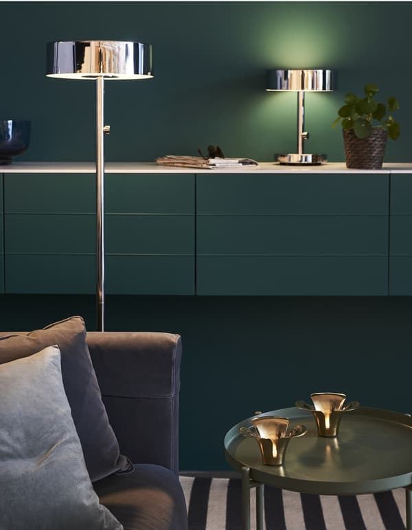 A mix of light sources in a living room: candles on a table, table lamp on a cabinet, and floor lamp next to the sofa.