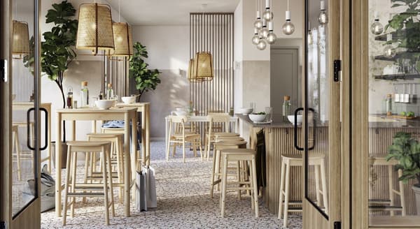 A modern café interior with a warm, Scandinavian-inspired design. The space features terrazzo flooring with colorful speckles and light wood furnishings, including high tables, standard tables, stools, and chairs. Rattan pendant lights hang above the seating areas, while a cluster of glass bulb pendant lights adds ambiance over the bar. Large potted green plants provide a touch of nature. The walls are finished in soft neutral tones with vertical wooden slats dividing the space. Glass doors in the foreground give a glimpse into this inviting and airy environment, filled with natural light and minimalist decor.