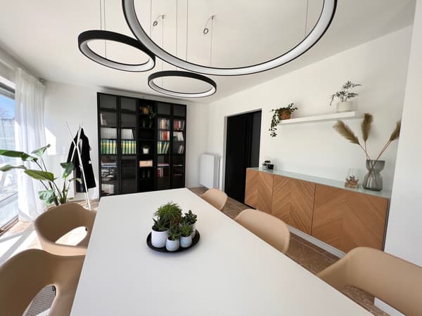 A modern dining room with a white table and beige chairs