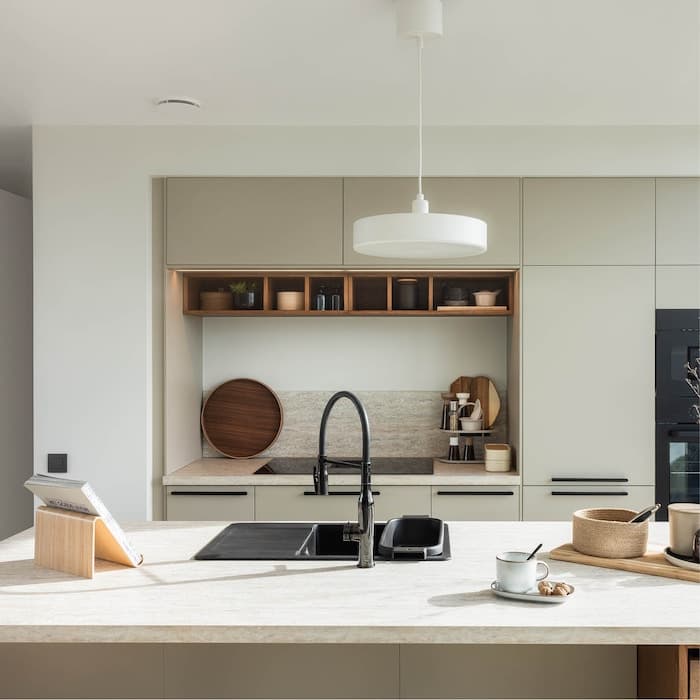A modern kitchen with a central island, a sink, and various kitchen utensils.