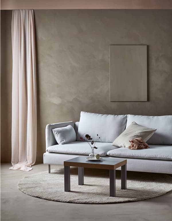 A modern sofa in a minimalist living room with a single piece of art on the wall and a simple sofa table