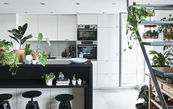 A monochrome kitchen and dining area with open staircase.