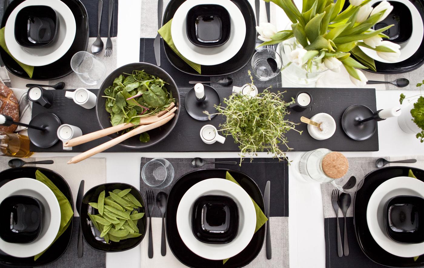 A monochrome table setting with bright green accents in plants, food and napkins.