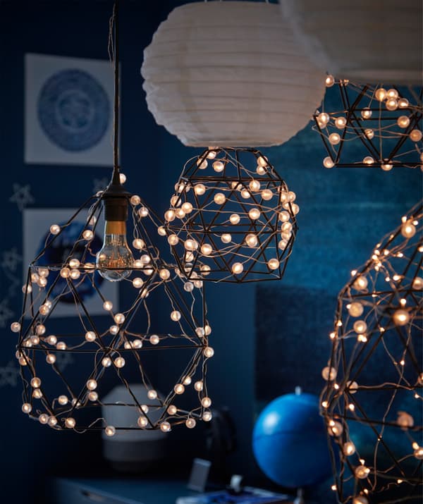 A moonlit, dark blue room section with astronomy decorations and lighting formed by SNÖYRA-wrapped BRUNSTA lamp shades.