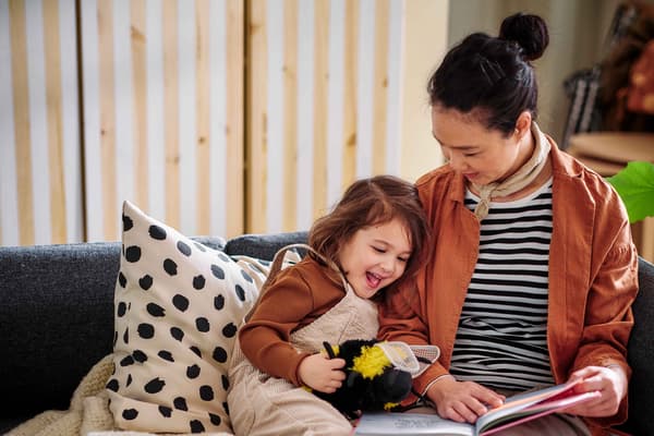 A mother reading a story to her daughter while sitting on a sofa.
