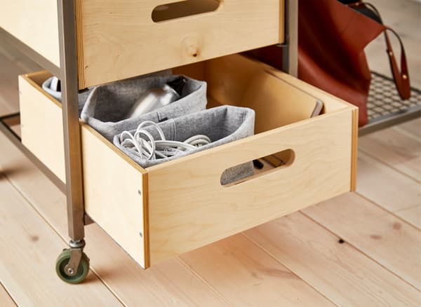A movable storage bench with castors next to a large dining table that’s being used as a study or work space. 