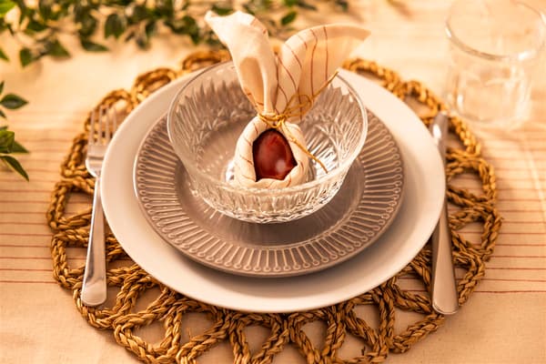 A napkin lies on a plate as a decoration, with a red egg inside it.