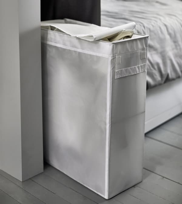 A narrow white laundry bag sits at the foot of the bed.