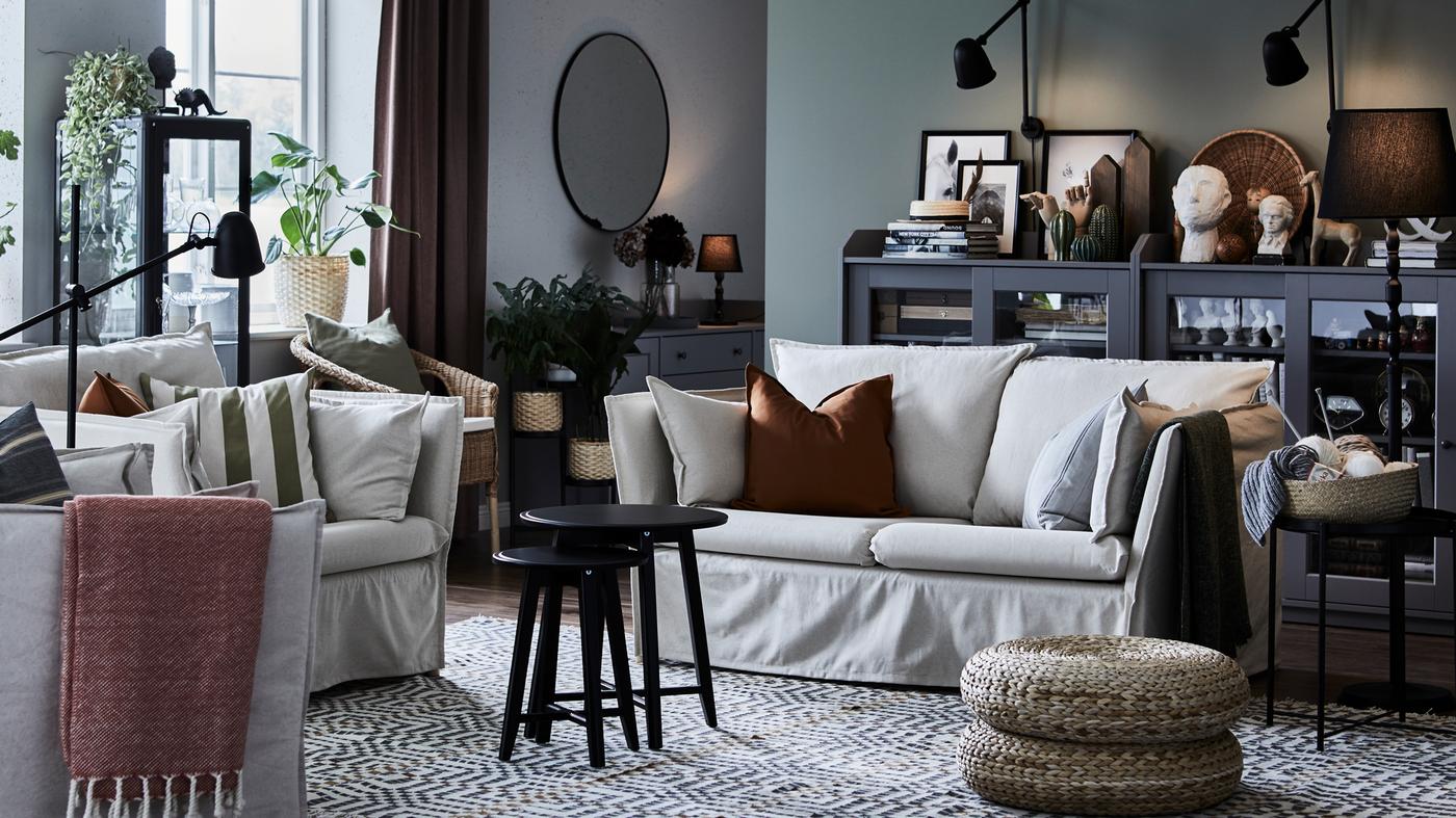 A natural-toned living room with a BACKSÄLEN two-seat sofa and large armchair around two black nested coffee tables.