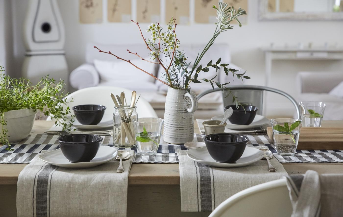A neutral-colored table setting with cotton napkins, simple place settings and a natural centrepiece.