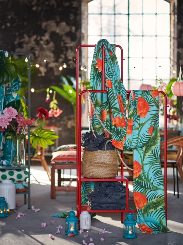 A NIKKEBY clothes rack draped in SOMMAR 2020 fabric and loaded with piles ofPOLARVIDE throws. Party decorations all around.