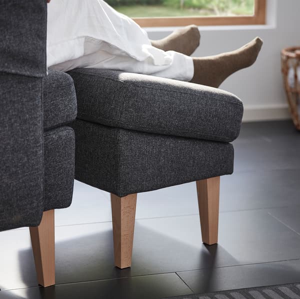 A pair of legs and feet resting on the OMTÄNKSAM footstool. Thanks to its angle it doesn’t disrupt blood circulation.