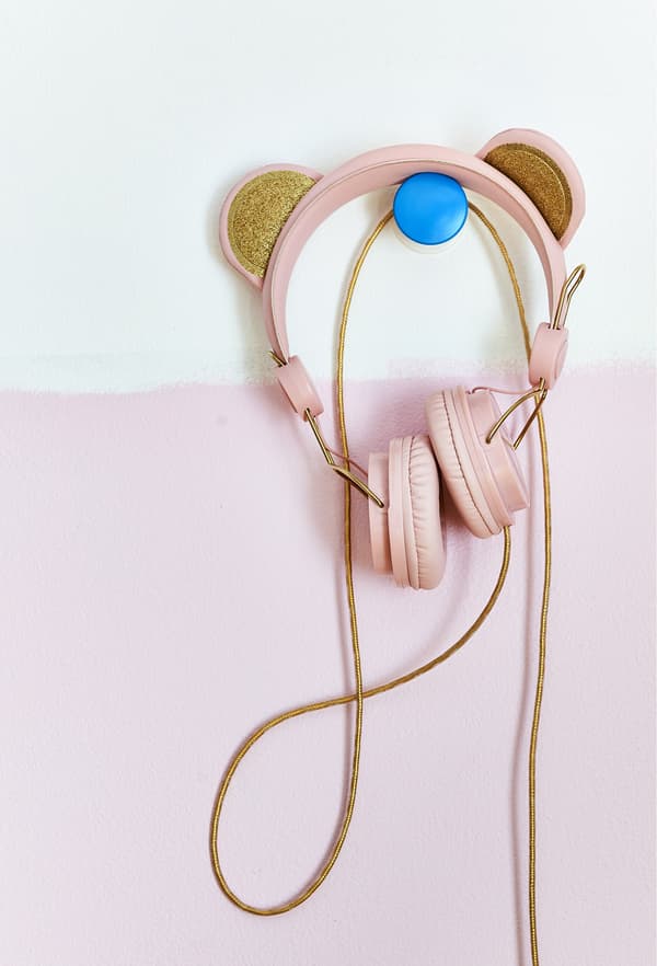 A pair of pink headphones hanging on a blue hook.