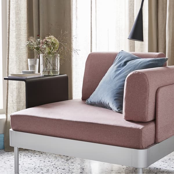 A pale pink armchair and black side table with a vase of flowers.