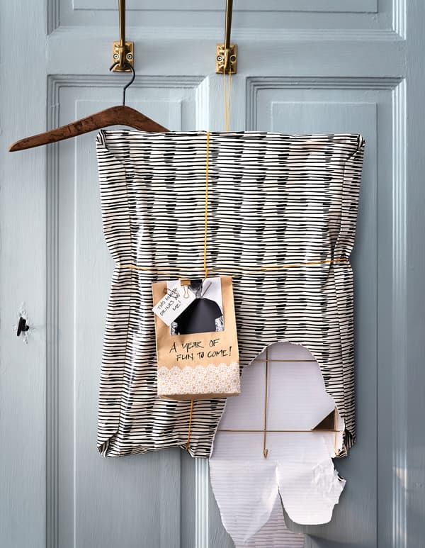 A partially unwrapped present, with homemade gift tag, hanging from a door hook.