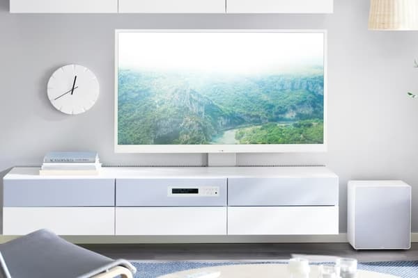A person clicks on a white remote control to control their smart TV.