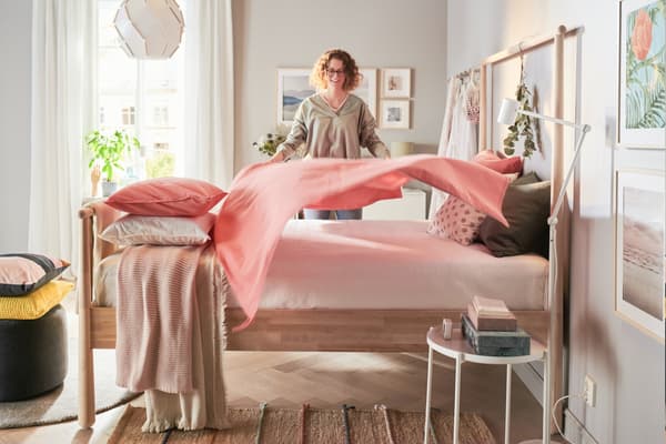 A person covers the bed with a blanket