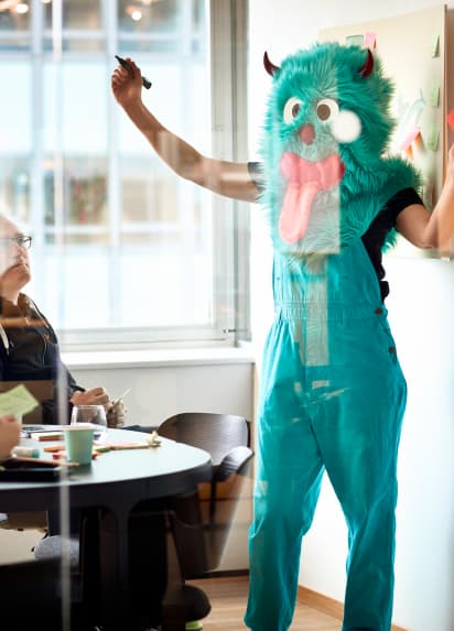 A person dressed up as a green monster with horns and its tongue out