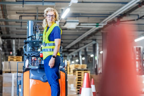 A person driving a forklift in a warehouse.