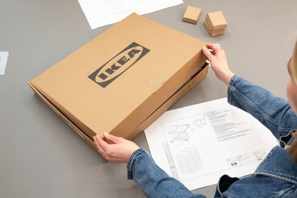 A person is packing an opened IKEA product back into a box and returning it.
