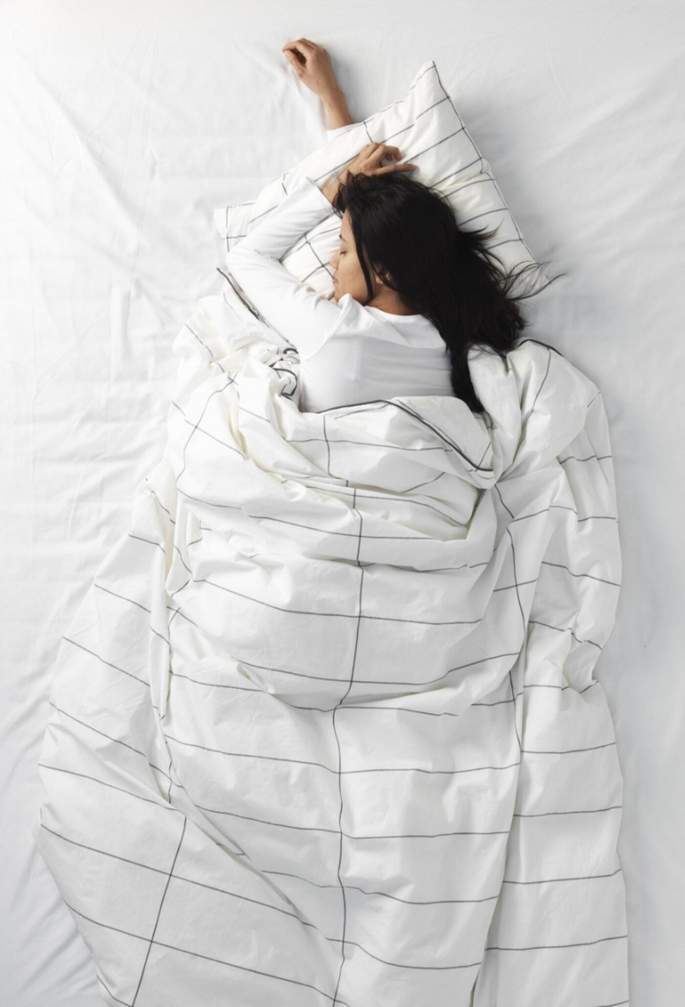 A person lying in her bed sleeping on her side.
