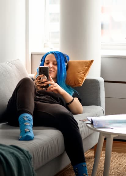 A person relaxing on a grey couch checking their phone