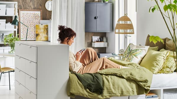 a person seats on the bed, while browshing on the mobile