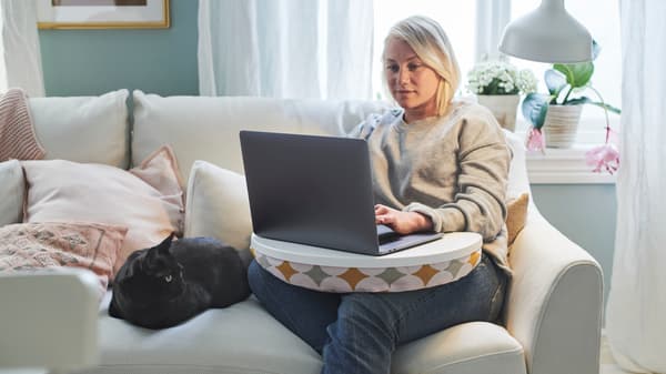 A person sitting with a laptop on her lap.