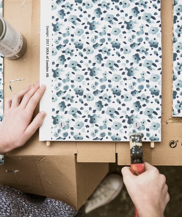 A person using a stapler on blue floral fabric.