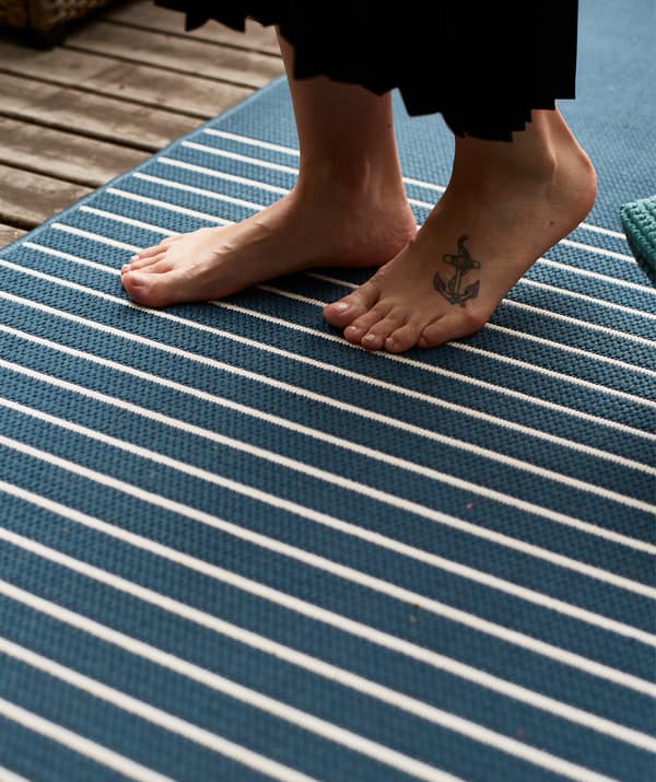 A person walks barefoot on a blue and white striped rug.