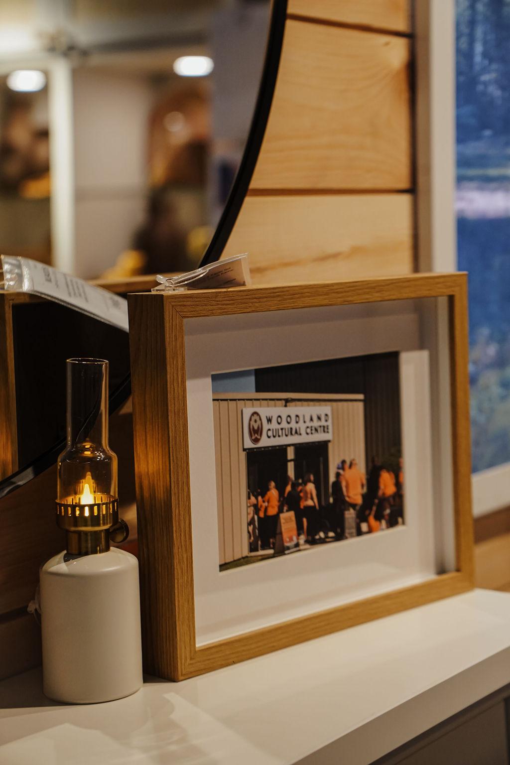 A picture and lantern sit on a ledge of a mantel.