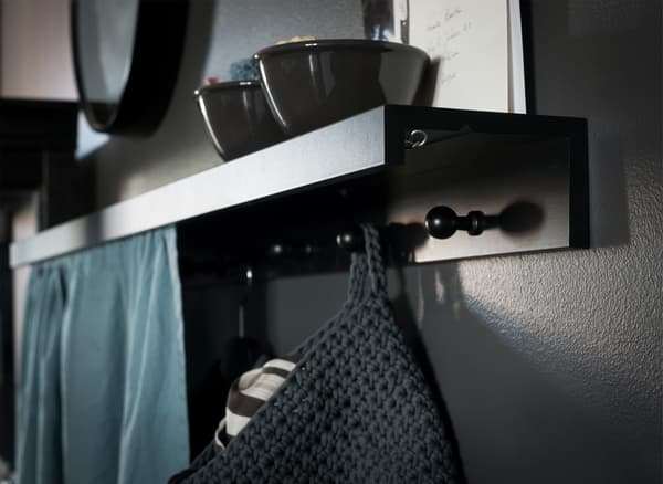 A picture ledge secured upside down as a DIY coat rack shelf with knobs attached and a fabric in front to hide clutter 