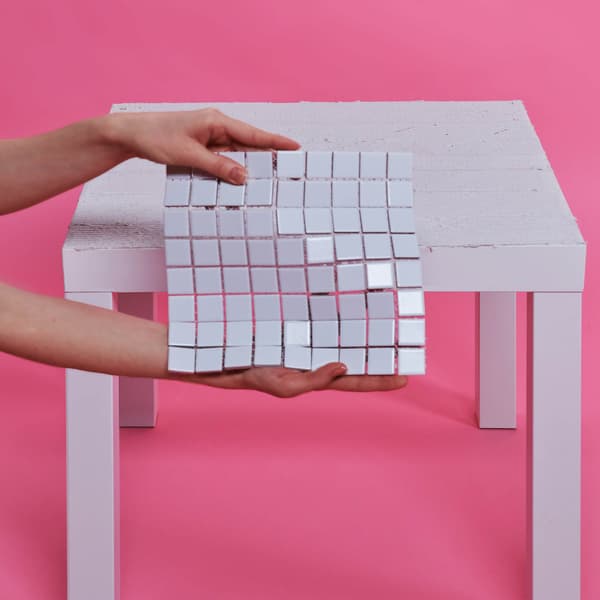 A piece of mosaic tile is held in front of the LACK table.