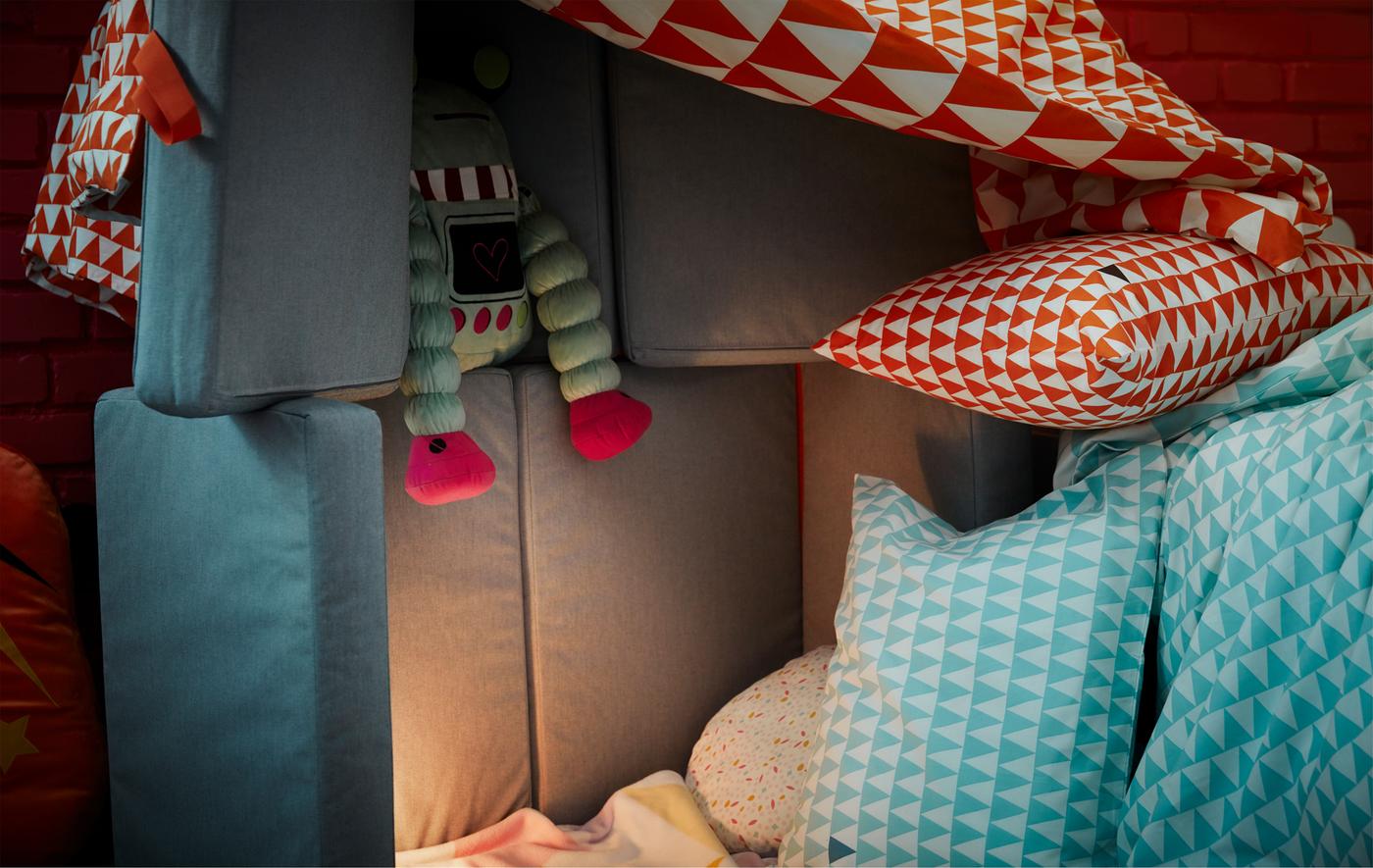 A pillow fort made from cushions, a sofa, and blankets