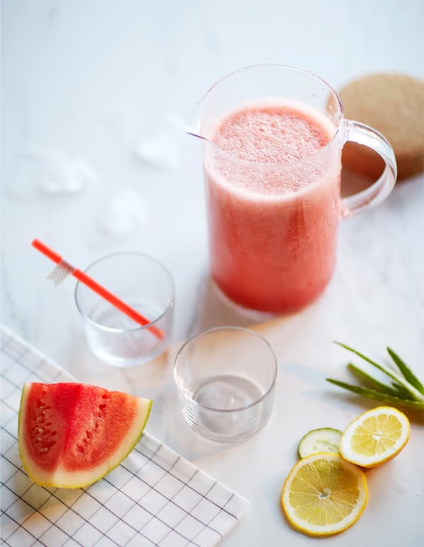 A pitcher of watermelon and cucumber smoothie is surrounded by ingredients.