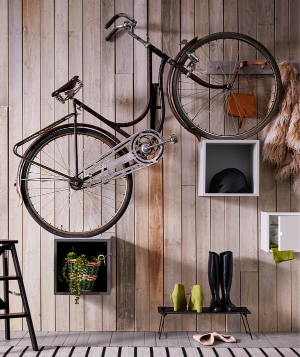 A plain bicycle placed with its wheels on EKET cabinets set at different heights, giving the bike a steep-uphill tilt.