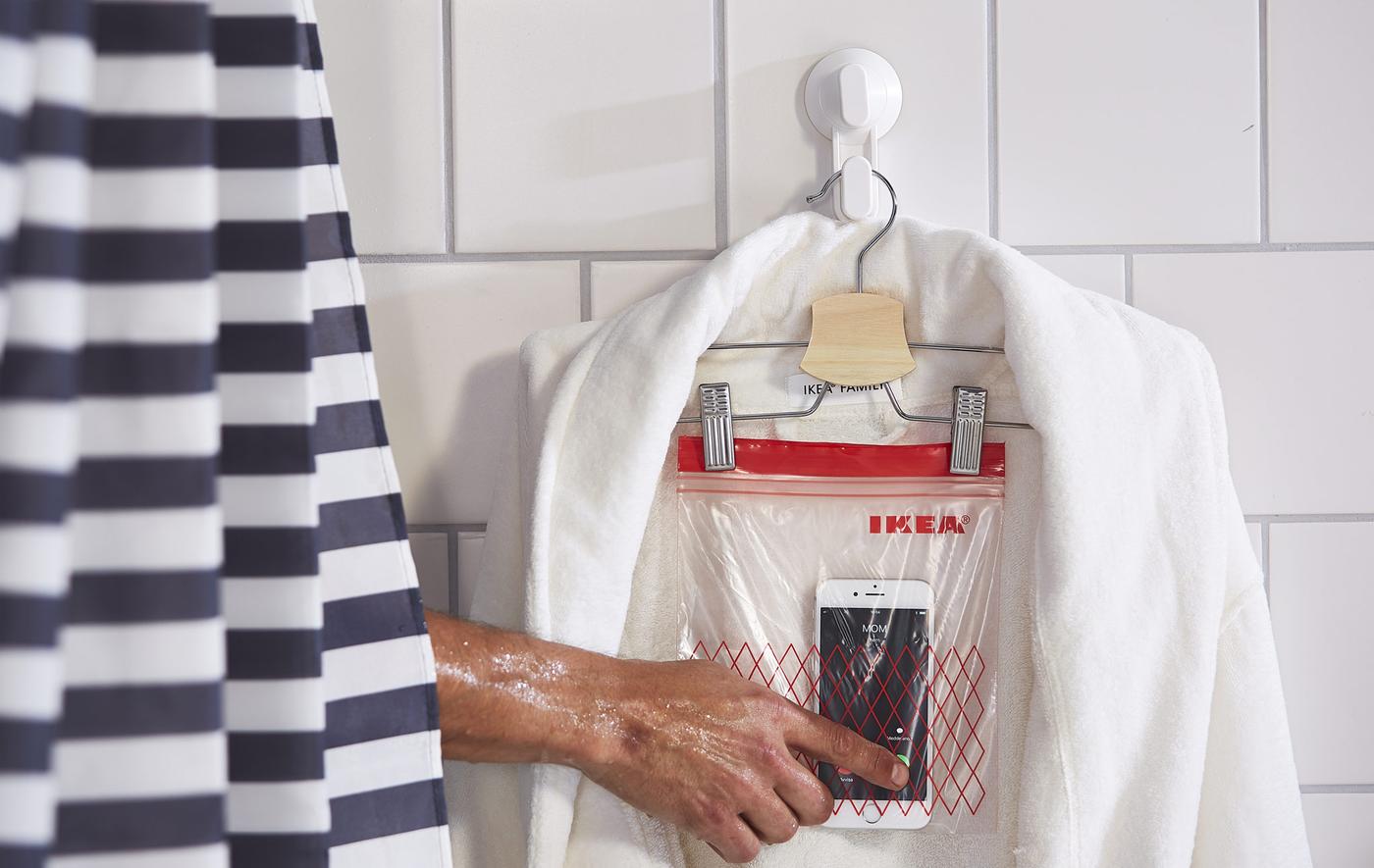 A plastic zip bag, pegged to a coat hanger, draped with a bath robe and used as a mobile phone holder.