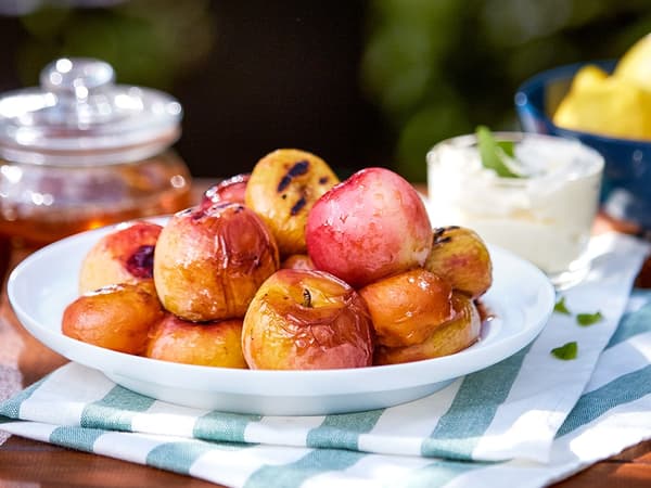 A plate of grilled peaches drizzled with honey.