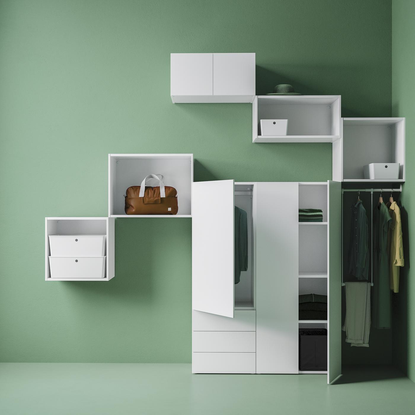 A PLATSA wardrobe and frames mounted on the wall are in a green room, along with some boxes and clothes hanging from a rail.