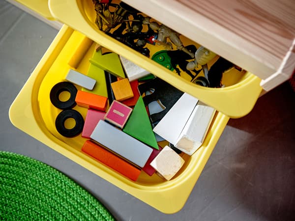 A playroom furnished with a storage unit and has lots of children’s toys.