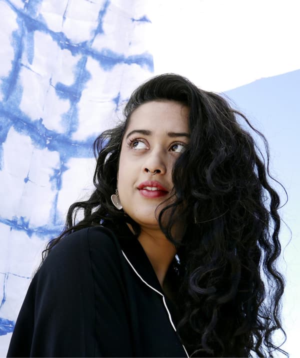 A portrait of Akanksha Deo, with a blue and white fabric backdrop.