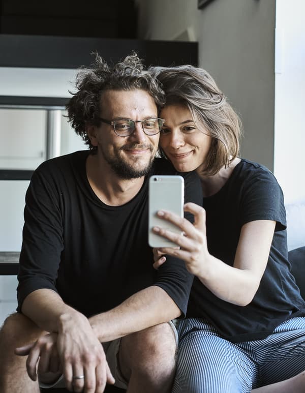 A portrait of Jurij and Konstancja taking a selfie on their stairs.